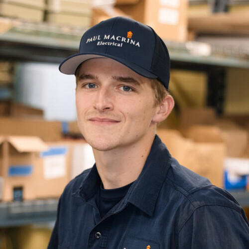 Young male Paul Macrina Electrical technician wearing company cap and work shirt in warehouse setting